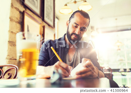 man with beer writing to notebook at bar or pub man with beer writing to notebook at bar or pub 41300964