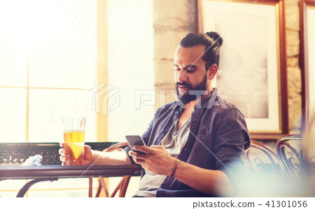 man with smartphone drinking beer at bar or pub man with smartphone drinking beer at bar or pub 41301056