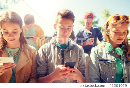 group of teenage friends with smartphones outdoors 41301059