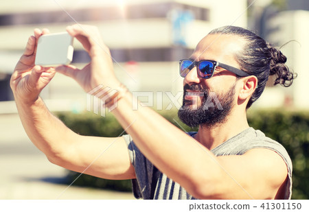 man taking video or selfie by smartphone in city 41301150