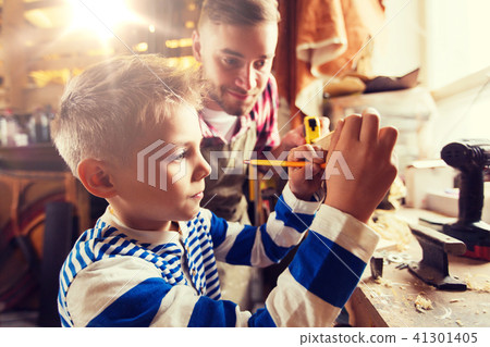 father and son with ruler measure wood at workshop 41301405