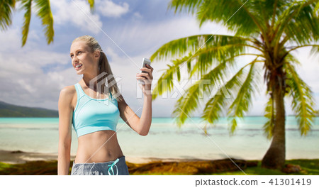 woman with smartphone doing sports over beach 41301419