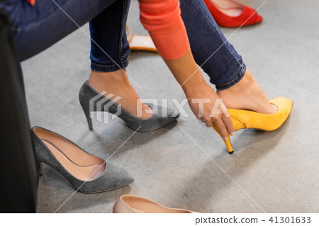young woman trying high-heeled shoes at store 41301633