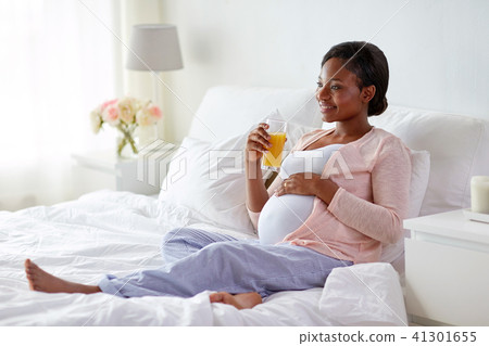 pregnant woman drinking orange juice in bed pregnant woman drinking orange juice in bed 41301655