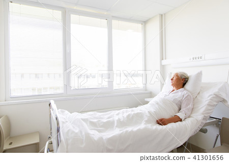 sad senior woman lying on bed at hospital ward sad senior woman lying on bed at hospital ward 41301656