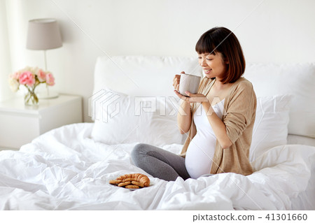 happy pregnant woman with cup drinking tea at home 41301660