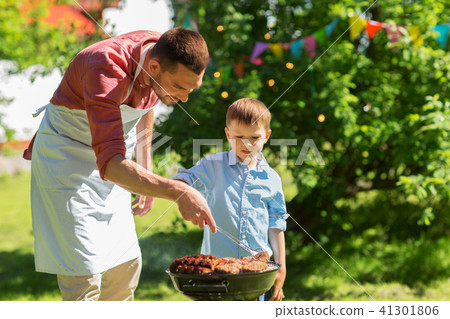 father and son cooking meat on barbecue grill father and son cooking meat on barbecue grill 41301806
