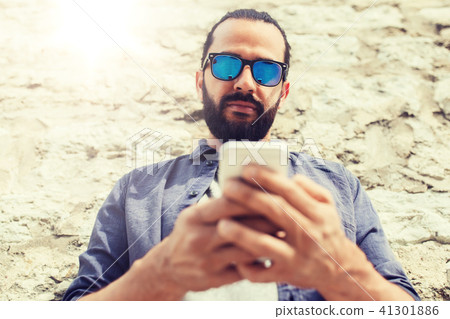 man texting message on smartphone at stone wall man texting message on smartphone at stone wall 41301886