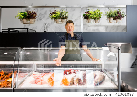 male seller showing seafood at fish shop fridge male seller showing seafood at fish shop fridge 41301888
