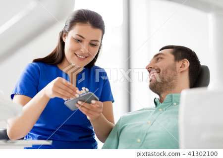 dentist choosing tooth color for patient at clinic 41302100