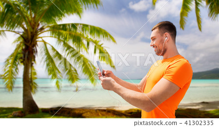 smiling young man with smartphone and earphones 41302335
