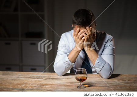 drunk man with glass of alcohol on table at night drunk man with glass of alcohol on table at night 41302386