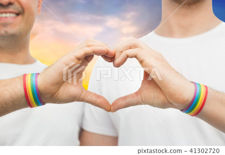 gay couple with rainbow wristbands and hand heart 41302720