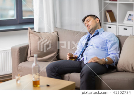 drunk man with glass of alcohol sleeping at home 41302784