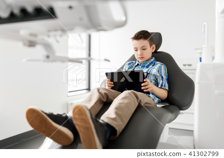 happy kid patient with tablet pc at dental clinic happy kid patient with tablet pc at dental clinic 41302799
