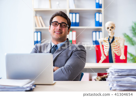 Businessman working with skeleton in office Businessman working with skeleton in office 41304654