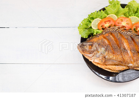 fried fish with vegetable on black dish. top view fried fish with vegetable on black dish. top view 41307187