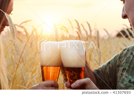 People drink beer in the wheat field during sunset People drink beer in the wheat field during sunset 41307693