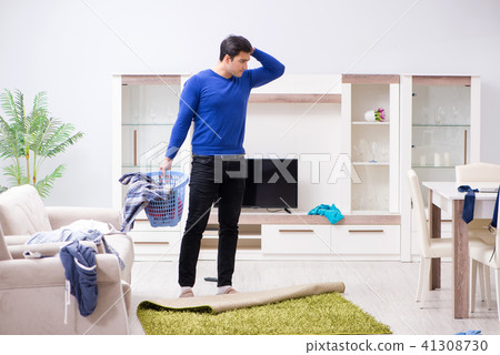 Young man collecting dirty clothing for laundry 41308730