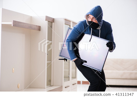 Man burglar stealing tv set from house Man burglar stealing tv set from house 41311347