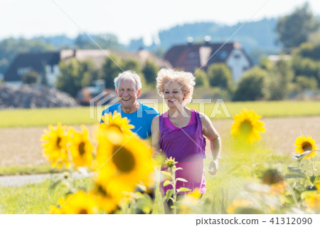 Cheerful senior couple jogging together outdoors in the countryside Cheerful senior couple jogging together outdoors in the countryside 41312090