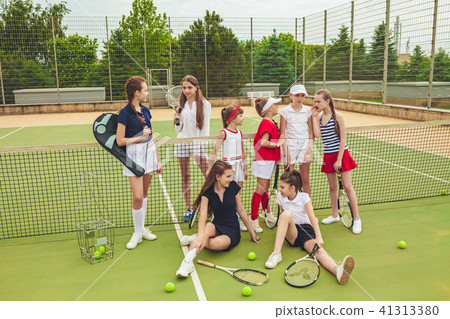 Portrait of group of girls as tennis players holding tennis racket against green grass of outdoor Portrait of group of girls as tennis players holding tennis racket against green grass of outdoor 41313380