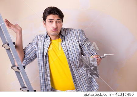 Young man applying plaster on wall at home 41315490