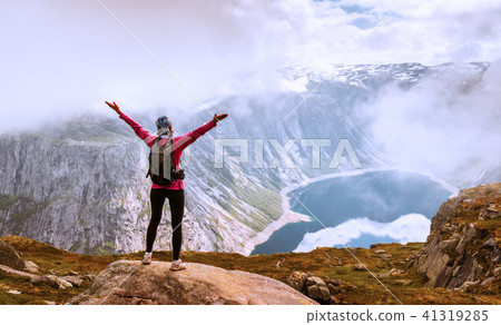 Young woman with backpack standing on fjord coast Young woman with backpack standing on fjord coast 41319285