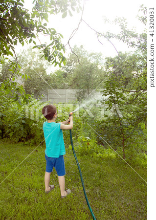 Boy playing with a sprinkler in the garden 41320031