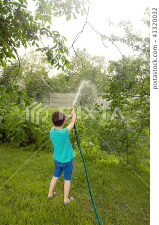 Boy playing with a sprinkler in the garden 41320032