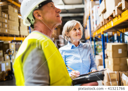 Senior woman manager and man worker working in a warehouse. Senior woman manager and man worker working in a warehouse. 41321766