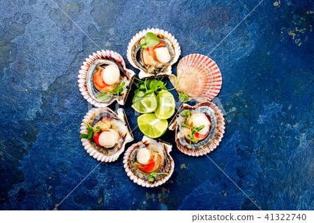 Raw opened shellfish scallops on blue background. Top view. Seafood concept Raw opened shellfish scallops on blue background. Top view. Seafood concept 41322740