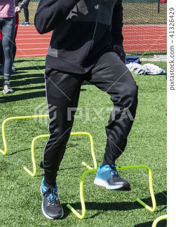 Stepping over yellow mini hurdles at practice 41326429
