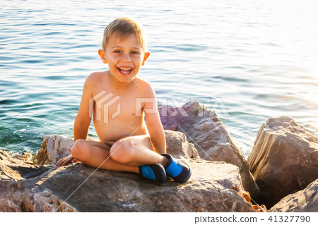 baby laughs sitting on the rocks 41327790