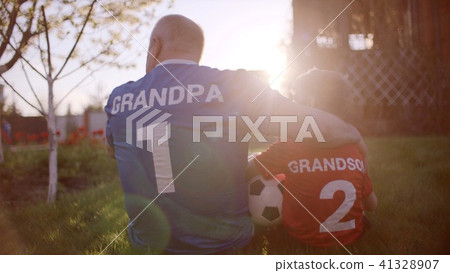 Backshot of grandfather and grandson on the lawn with soccer ball on sunset Backshot of grandfather and grandson on the lawn with soccer ball on sunset 41328907