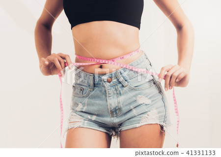 Slim woman measures her waist with measuring tape. 41331133