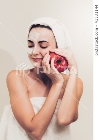 Woman get facial mask with tomato cream extract. Woman get facial mask with tomato cream extract. 41331144