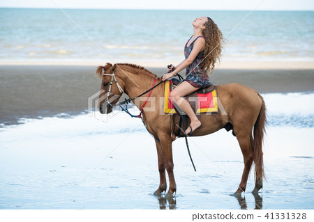 Woman fashion model riding a horse on the beach. 41331328