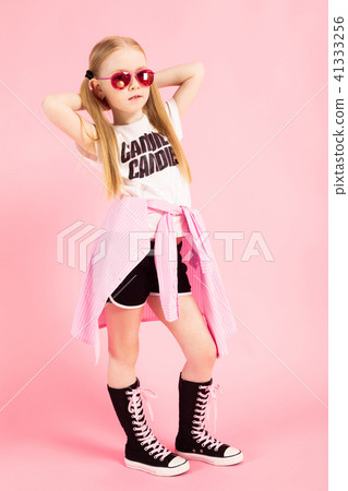 Girl with red tails on a pink background. A charming girl in bright sports clothes and pink glasses 41333256