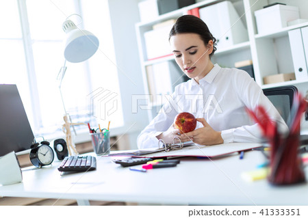 Young girl in the office working with documents and holding an apple. 41333351