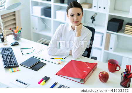 A young girl is sitting at the computer desk in the office. 41333372