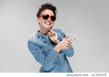 Young brunette girl with glasses in the form of a heart. The hairs are gathered in a bun. The girl Young brunette girl with glasses in the form of a heart. The hairs are gathered in a bun. The girl 41333570