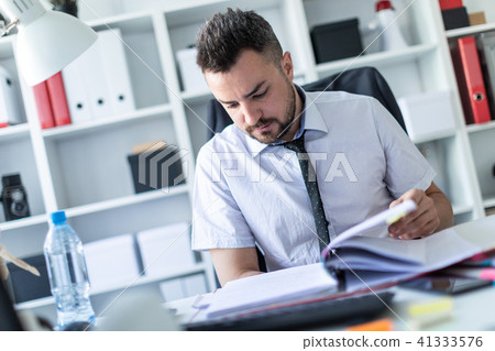 A man is sitting in the office and scrolls through the documents. A man is sitting in the office and scrolls through the documents. 41333576