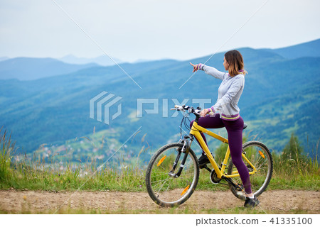 Young happy woman riding bicycle in the mountains at summer day 41335100