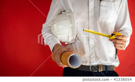Engineer holding helmet, tape measure and drawing Engineer holding helmet, tape measure and drawing 41336054