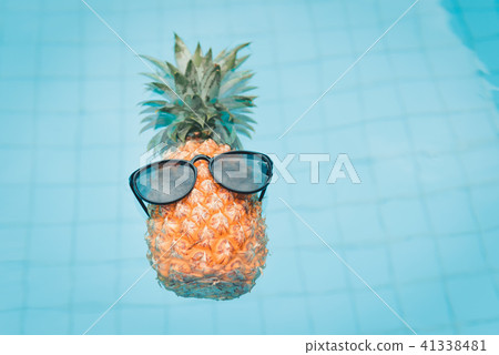 Pineapple wearing sunglasses in swimming pool 41338481