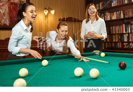 Young women playing billiards at office after work. Young women playing billiards at office after work. 41340003