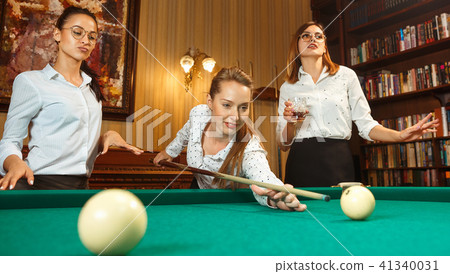 Young women playing billiards at office after work. Young women playing billiards at office after work. 41340031