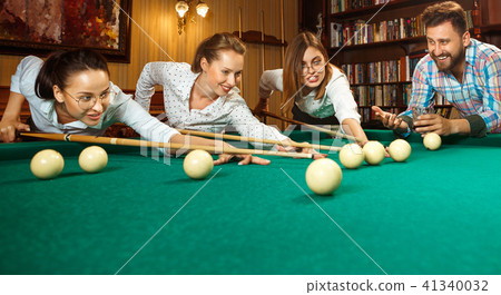Young men and women playing billiards at office after work. Young men and women playing billiards at office after work. 41340032