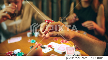 Side view photo of friends sitting at wooden table. Friends having fun while playing board game. Side view photo of friends sitting at wooden table. Friends having fun while playing board game. 41340048